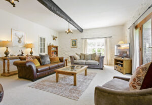 Cosy cottage living room with leather sofas, oak beams and exposed stone wall.
