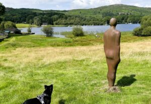 Dog looking at an Anthony Gormley statue at Coniston Water
