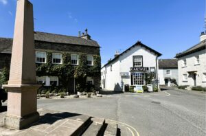 The historic Cartmel village square featuring traditional stone buildings.