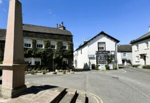 The historic Cartmel village square featuring traditional stone buildings.