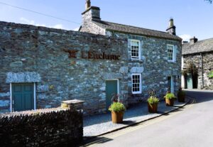 The exterior of L’Enclume restaurant in Cartmel, showing the historic stone building.