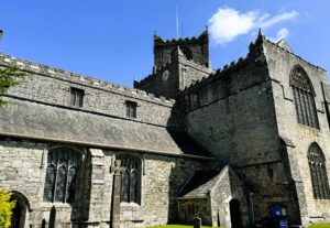 The medieval Cartmel Priory standing tall against a clear spring sky.