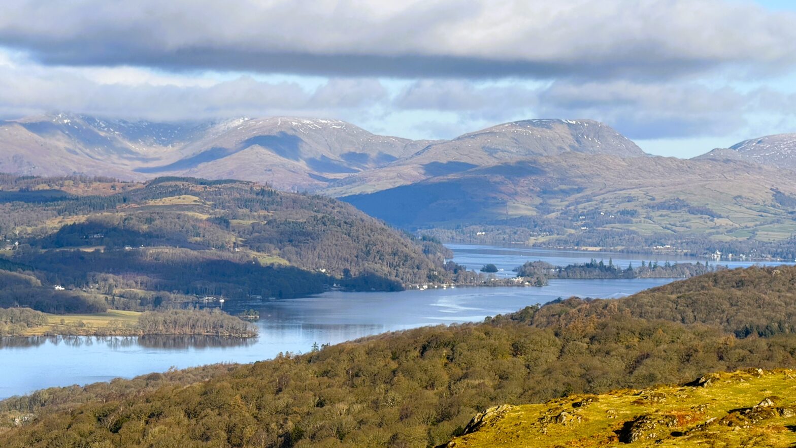 Snow capped fells and a still, reflective lake Windermere in the Lake District during the quiet low season.