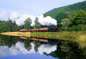 "A steam engine pulling passenger carriages through the countryside along the Leven River