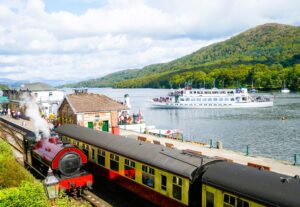 A steam engine at Lake Windermere eith a Windermere Cruise Steamer in the background.