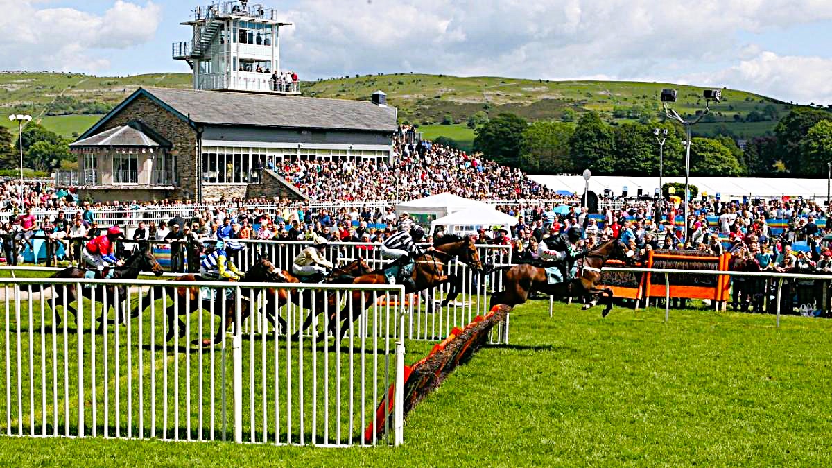 Thrilling Cartmel Races action with horses jumping the fences.