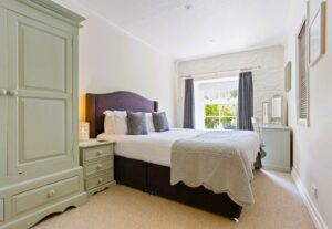 A bright bedroom featuring a king-size bed with a plush padded headboard