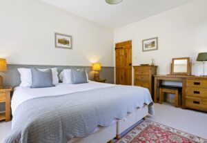 Spacious bedroom featuring a super king-size bed with crisp white linens, a wooden headboard, and a matching bedside table.