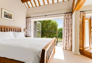 Bright bedroom at Cartmel Hill holiday cottage with slide and fold doors opening onto the veranda